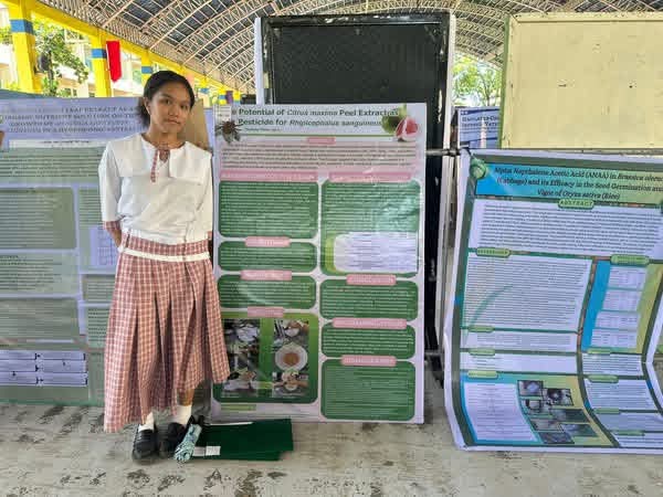 Student researcher standing beside a project display board