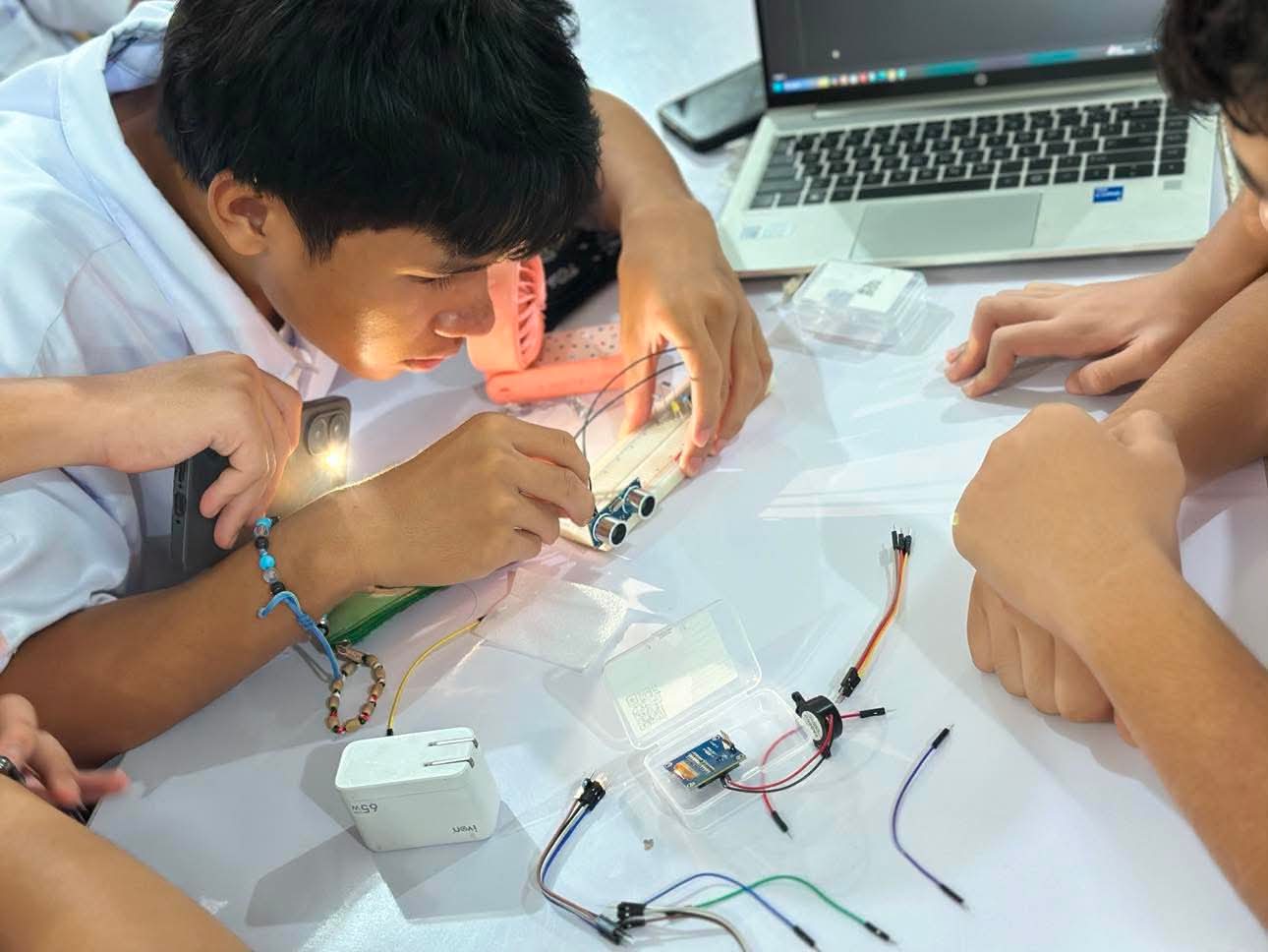 Student assembling an electronics prototype at a worktable