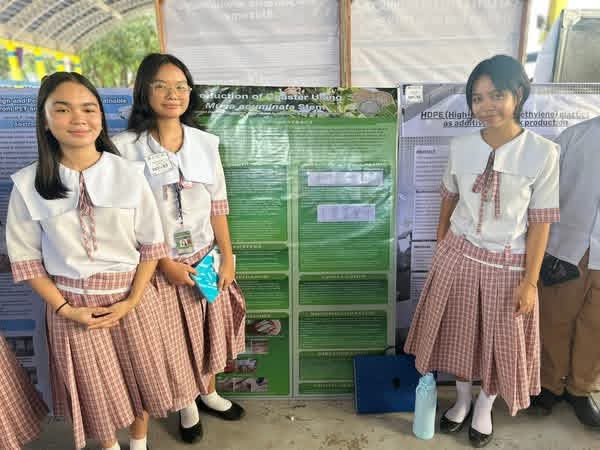 Three student researchers standing beside their investigatory project poster